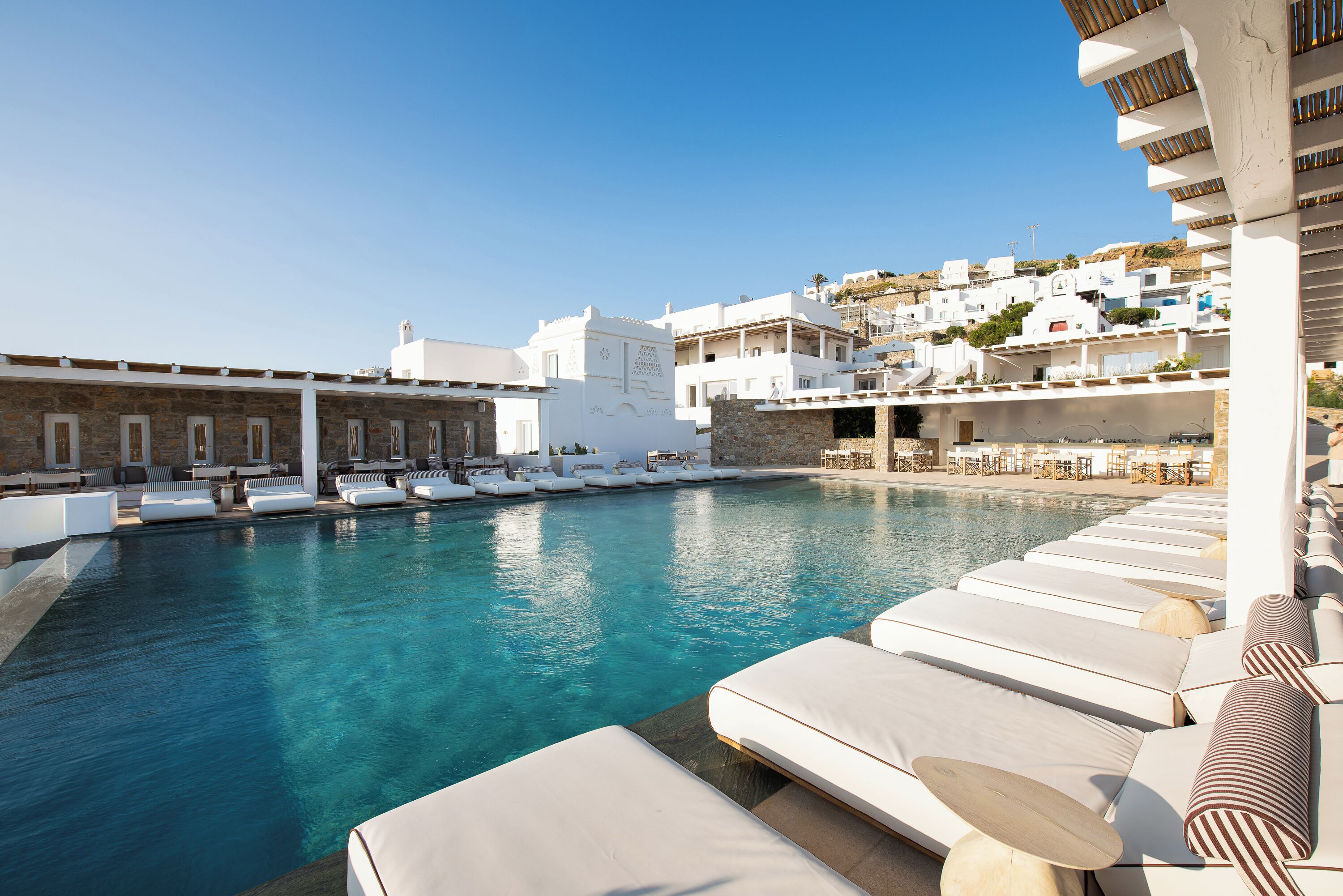 A poolside area with lounge chairs and a view of white buildings in the background.