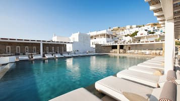A poolside area with lounge chairs and a view of white buildings in the background.