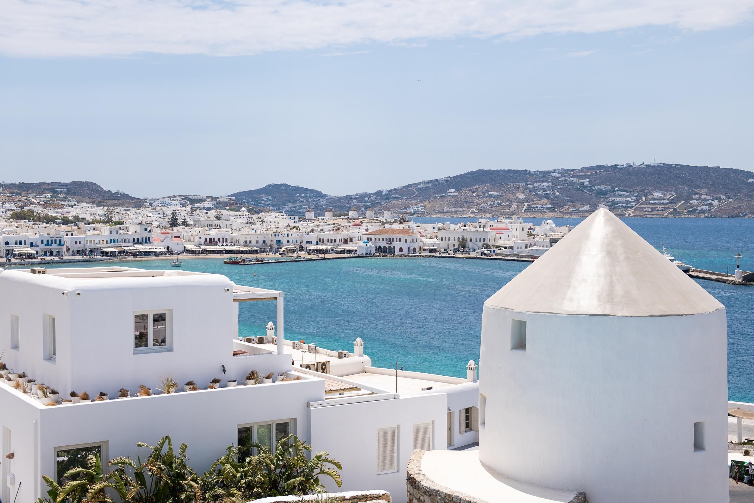 A coastal town with white buildings, a prominent conical structure, and a clear view of the sea.