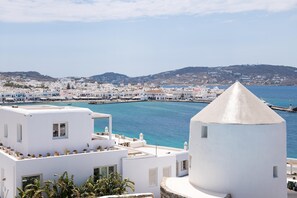 A coastal town with white buildings, a prominent conical structure, and a clear view of the sea.
