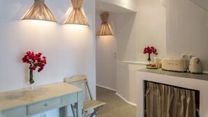 A modern kitchen with white cabinets, a dining table with chairs, and two wall-mounted lamps.