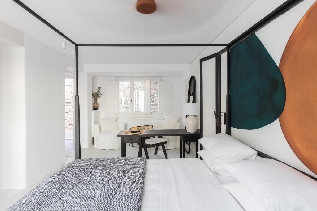 A modern hotel room with a bed, a desk, and a seating area.