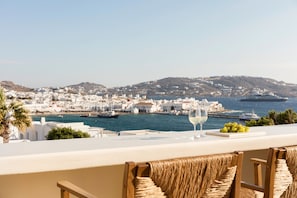 A terrace with wicker chairs, a glass of white wine, and a plate of grapes. - Porto Mykonos Hotel (Mykonos)