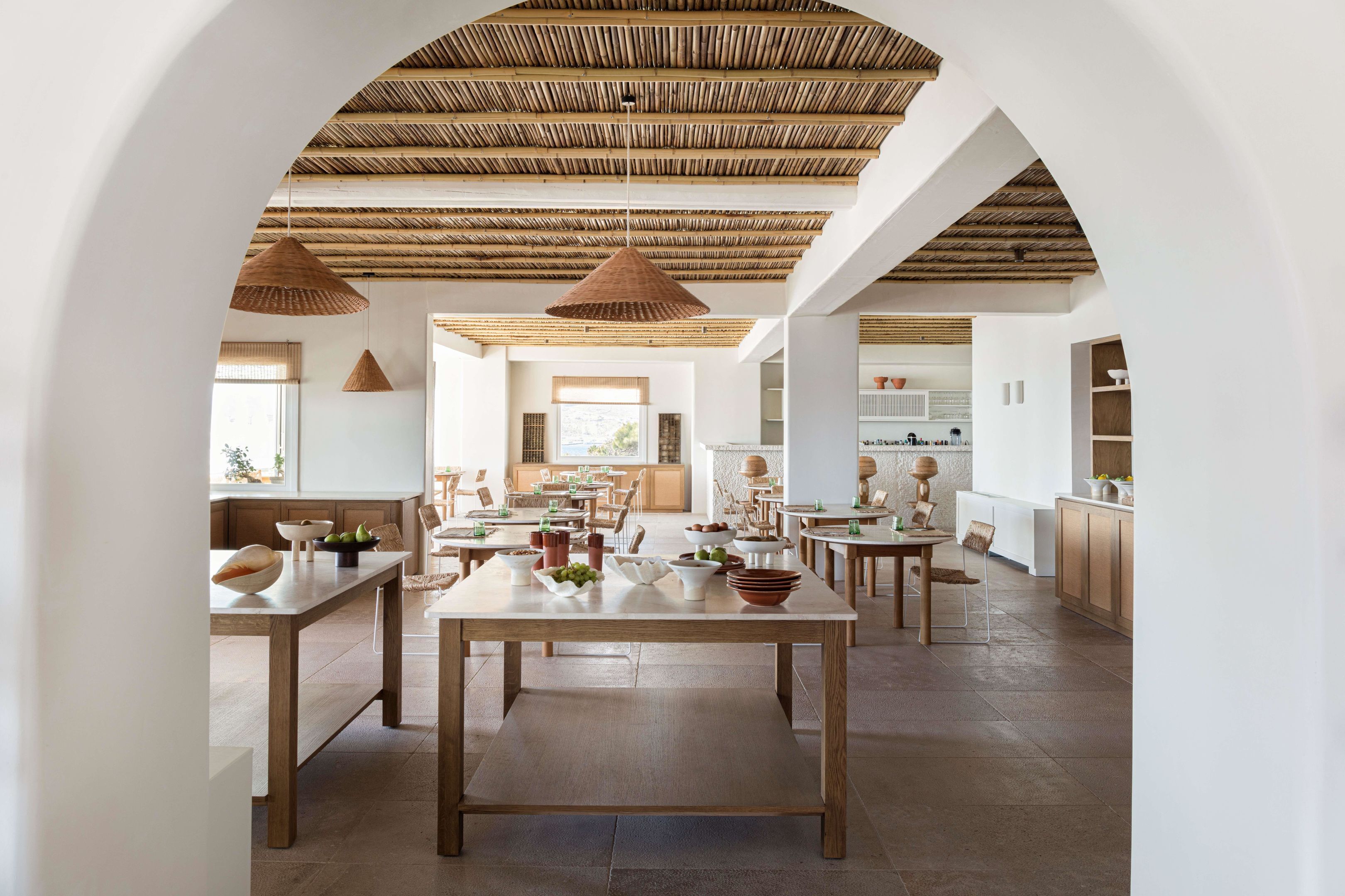 A spacious dining area with high ceilings, wooden tables, and hanging light fixtures.