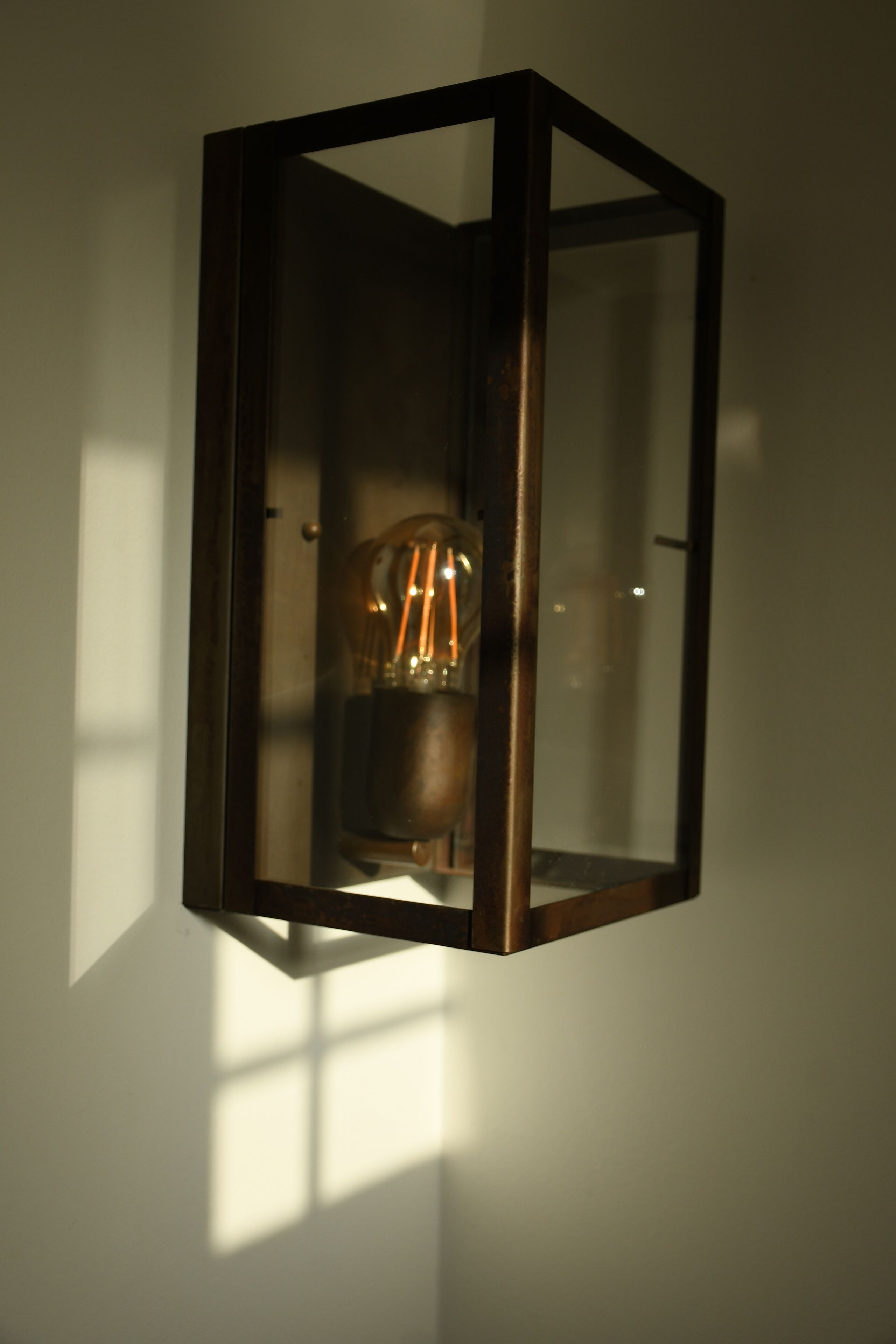 A wall-mounted light fixture with a glass enclosure and visible filament bulbs.