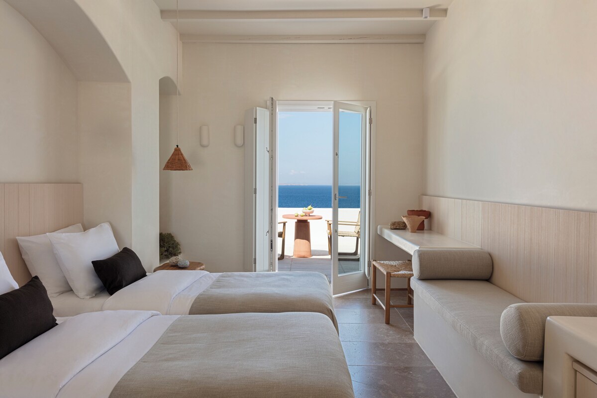 Ein Hotelzimmer mit zwei Betten, einem Balkon und Meerblick.