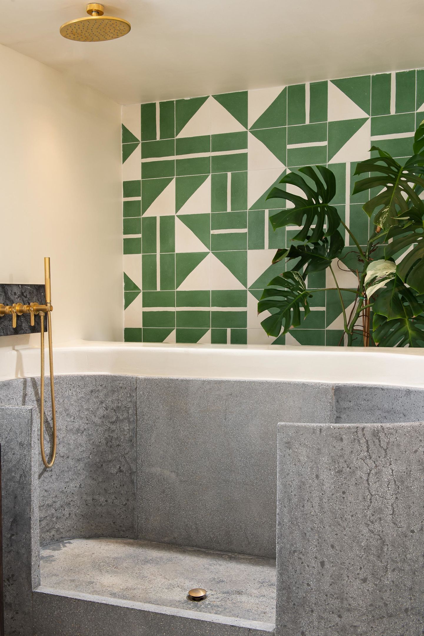 Une salle de bain avec une baignoire, une douche et un mur recouvert de carreaux verts.