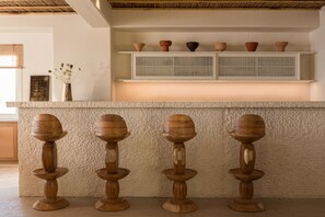 A kitchen with a central island, a shelf with decorative bowls, and a vase with flowers. - Porto Mykonos Hotel (Mykonos)
