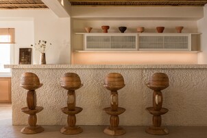 Una cocina con una isla central, un estante con cuencos decorativos y un florero con flores.