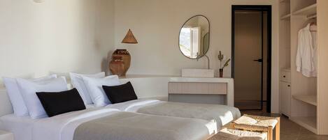 A hotel room with a large bed, a bedside table, a mirror, a wardrobe, and a bathroom with a sink and mirror.