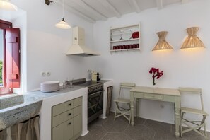 A compact kitchen with a stove, oven, and hanging light fixtures. - Porto Mykonos Hotel (Mykonos)