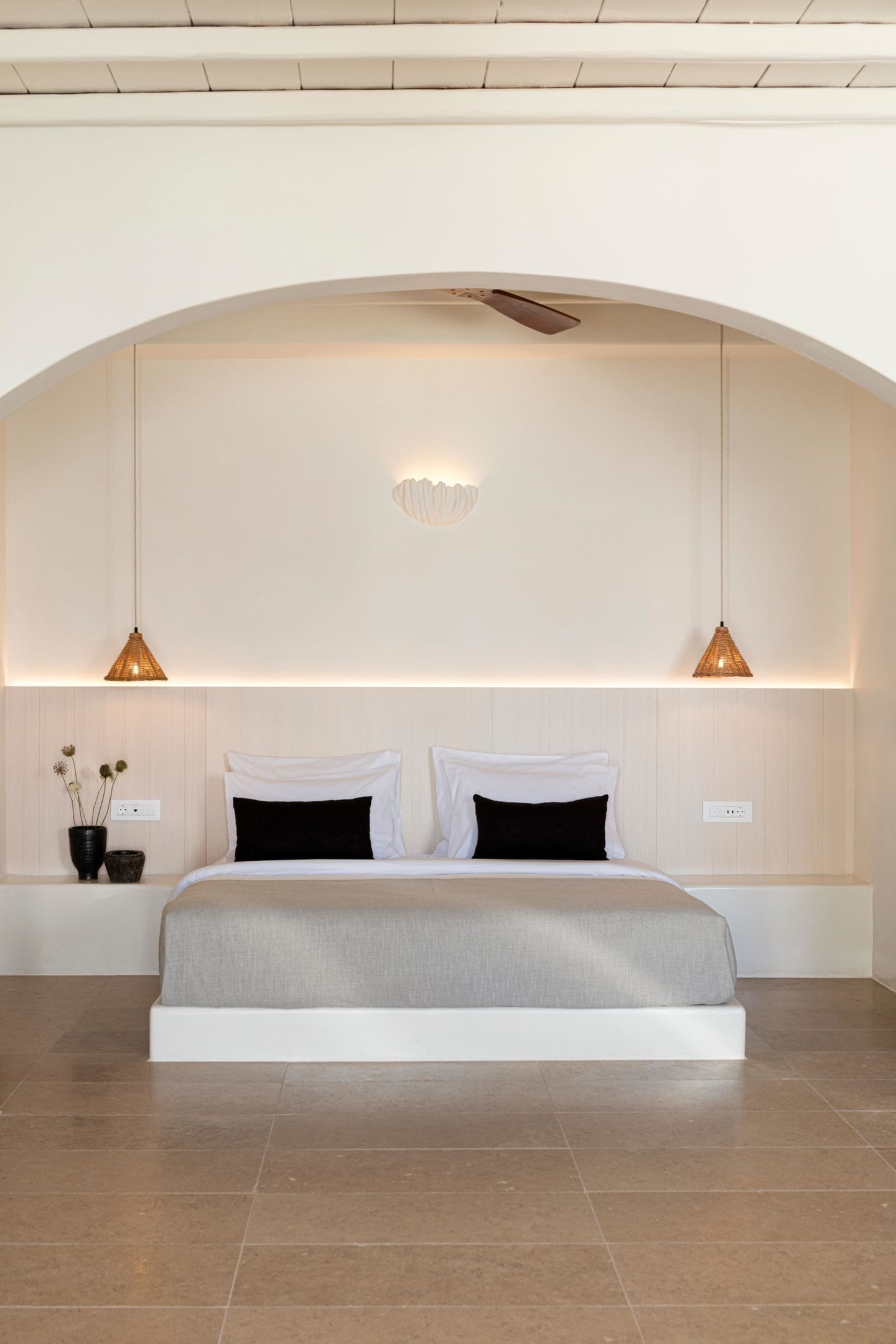 A modern bedroom with a large bed, two bedside lamps, and a wall-mounted light fixture.