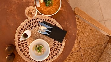A round table with two bowls of food, a napkin, cutlery, and a glass.