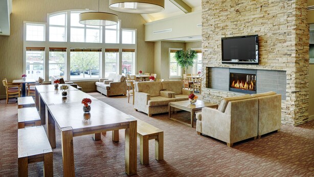 Un salón amplio con chimenea, asientos cómodos y ventanas grandes.