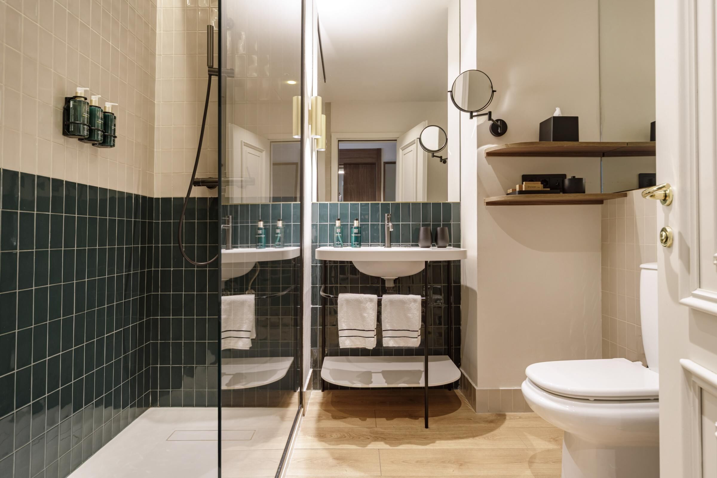 Ein modernes Badezimmer mit einer Duschkabine, zwei Waschbecken, einer Toilette und einem Spiegel.