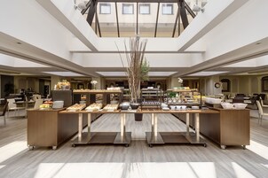 Un'ampia sala da pranzo moderna con un'area centrale per il servizio, soffitti alti e luce naturale.
