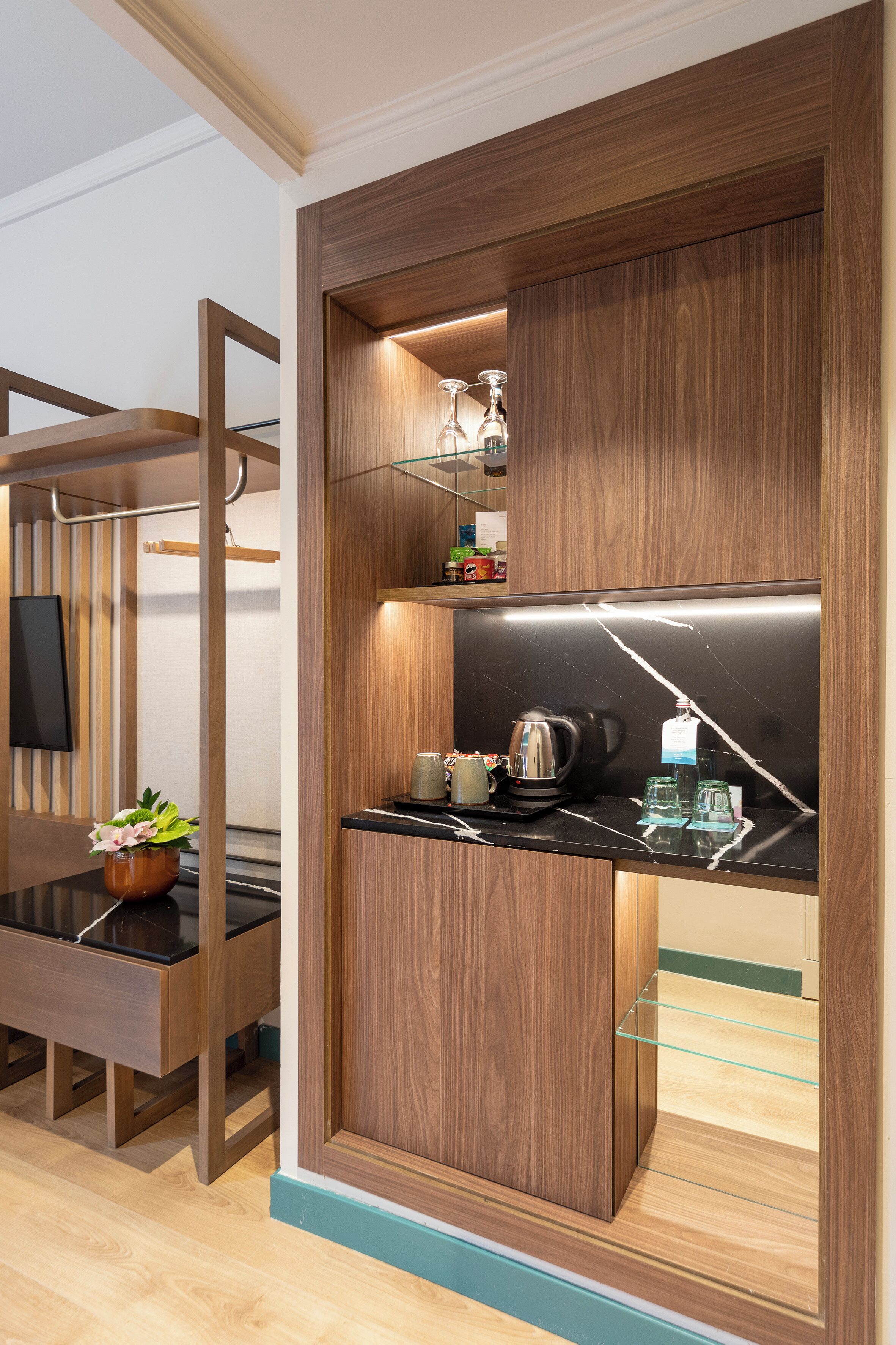A modern kitchen with wooden cabinetry, a black countertop, and a built-in shelf with kitchenware.