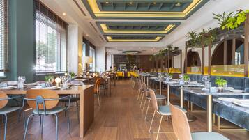 Un restaurante espacioso con mesas largas y cabinas, suelo de madera y un diseño de techo moderno.