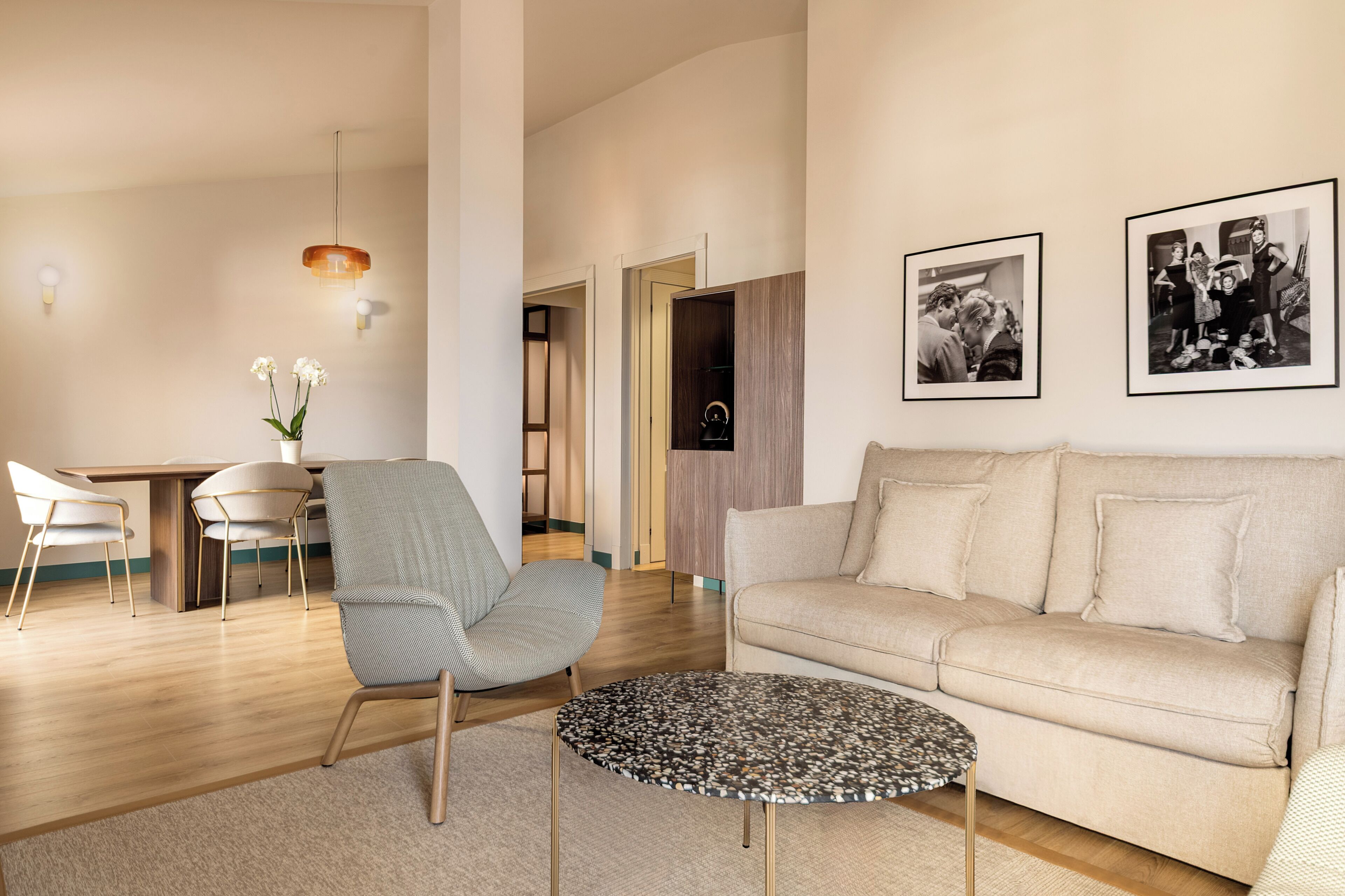 A modern living room with a sofa, a round coffee table, and a dining area with chairs.
