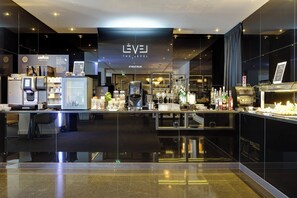 Uma área de bar moderna com design elegante, incluindo uma máquina de café, prateleiras com garrafas e um display de cardápio.