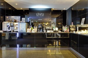 Zona bar moderna con un design elegante, che comprende una macchina da caffè, scaffali con bottiglie e un espositore per il menu.
