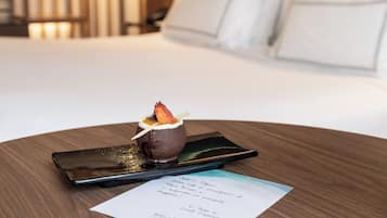 Un dessert su un vassoio con un menu appoggiato su un tavolo di legno in una camera d'albergo.