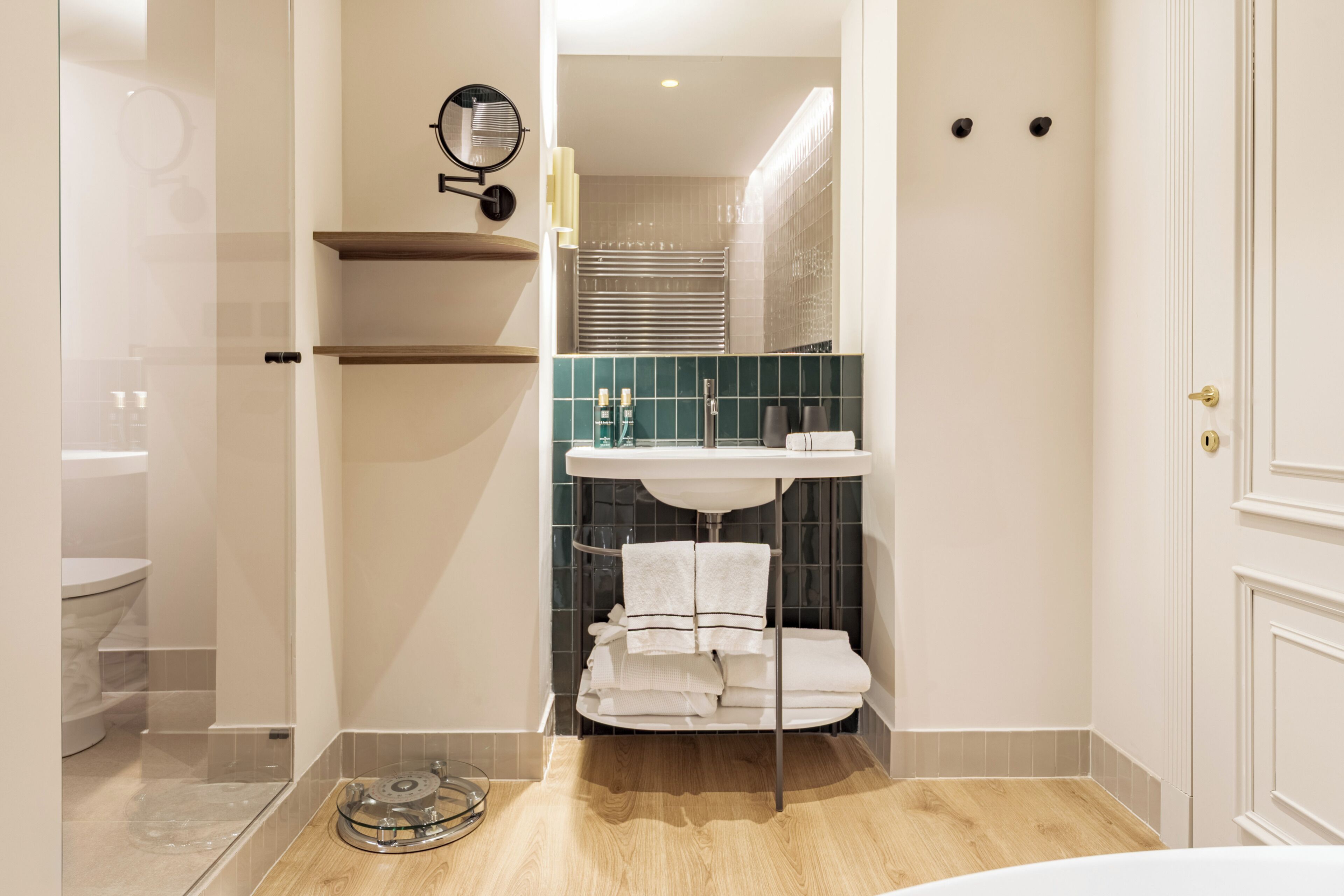 Un baño moderno con cabina de ducha de vidrio, tocador con lavamanos y perchero.