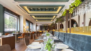 A restaurant with a long dining table set for a meal, surrounded by chairs and a sofa. - Melia Milano (Milan)