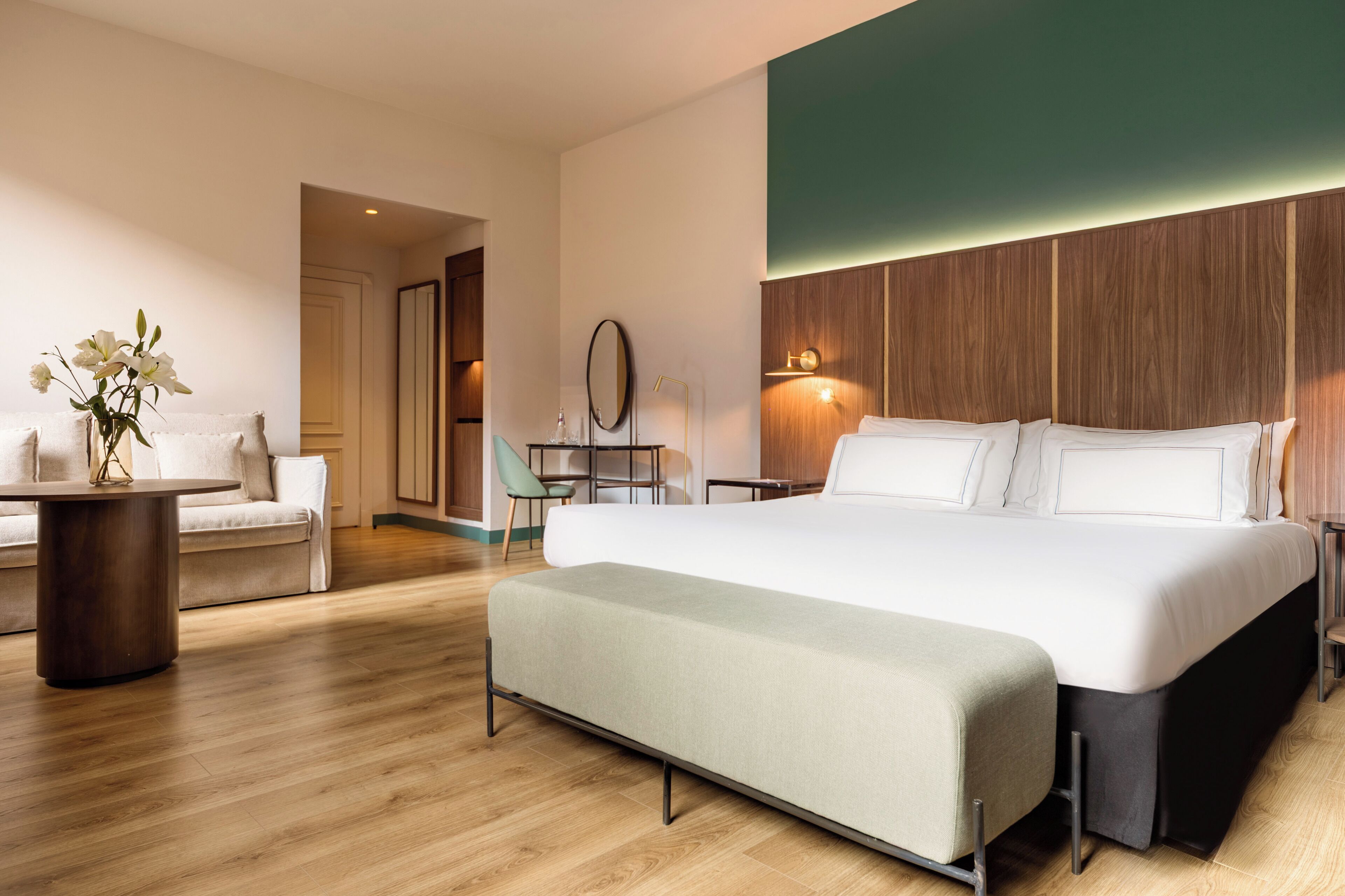Une chambre d’hôtel moderne avec un grand lit, une petite table, un canapé et un vase de fleurs.