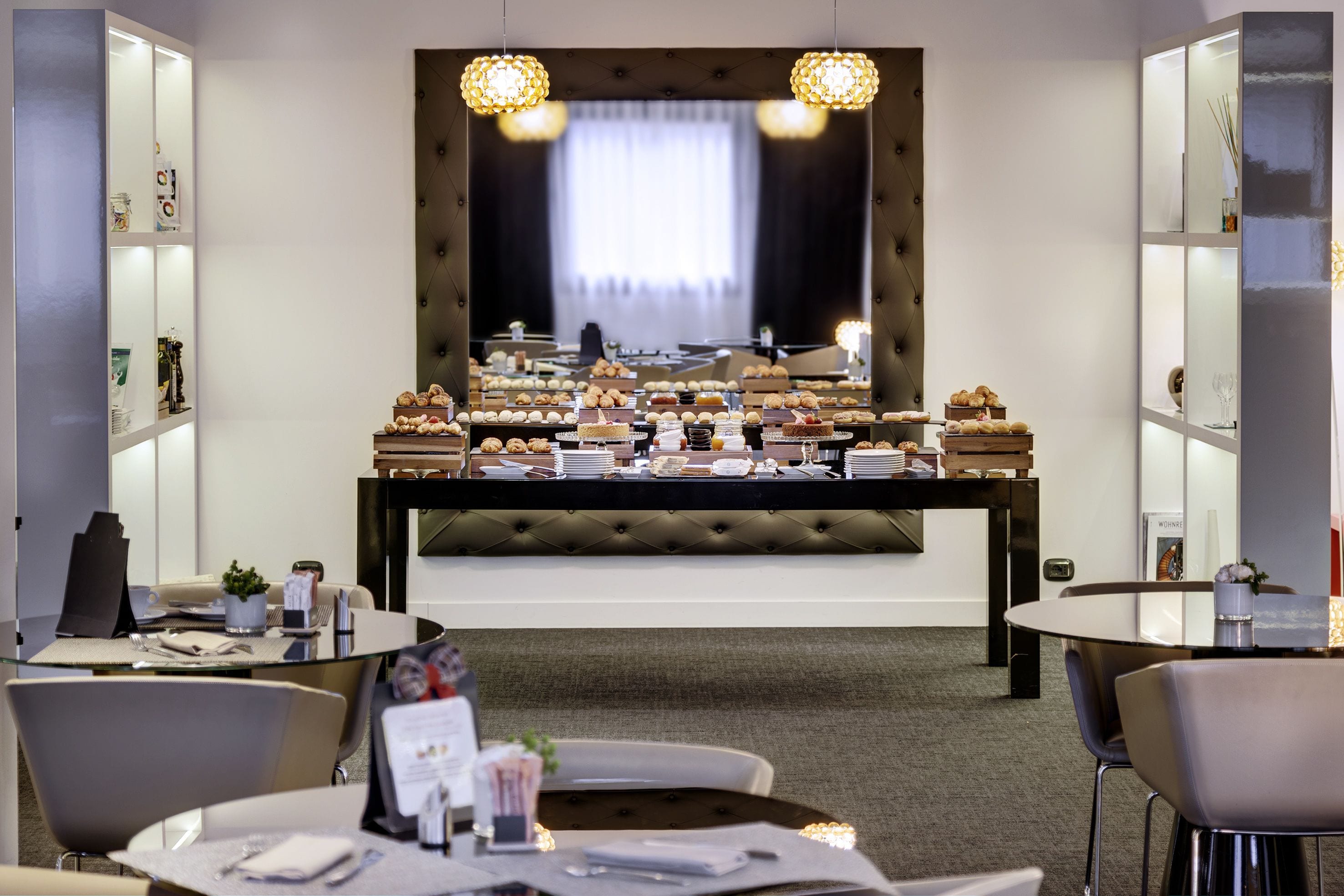 Ein Hotelzimmer mit Essbereich, der ein Buffet, einen großen Spiegel und moderne Möbel beherbergt.