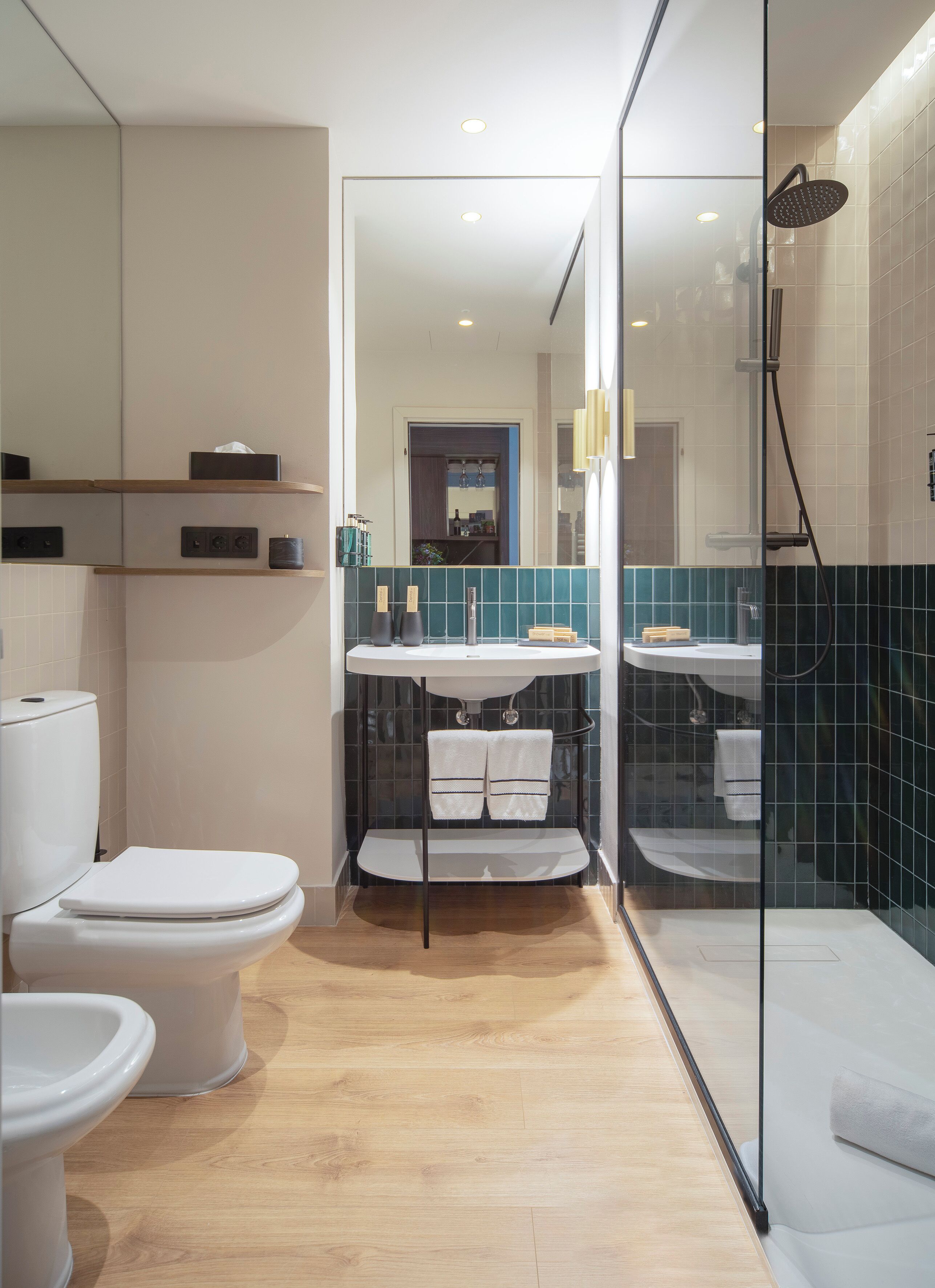Un baño moderno con inodoro, bidé y cabina de ducha con paredes de vidrio.