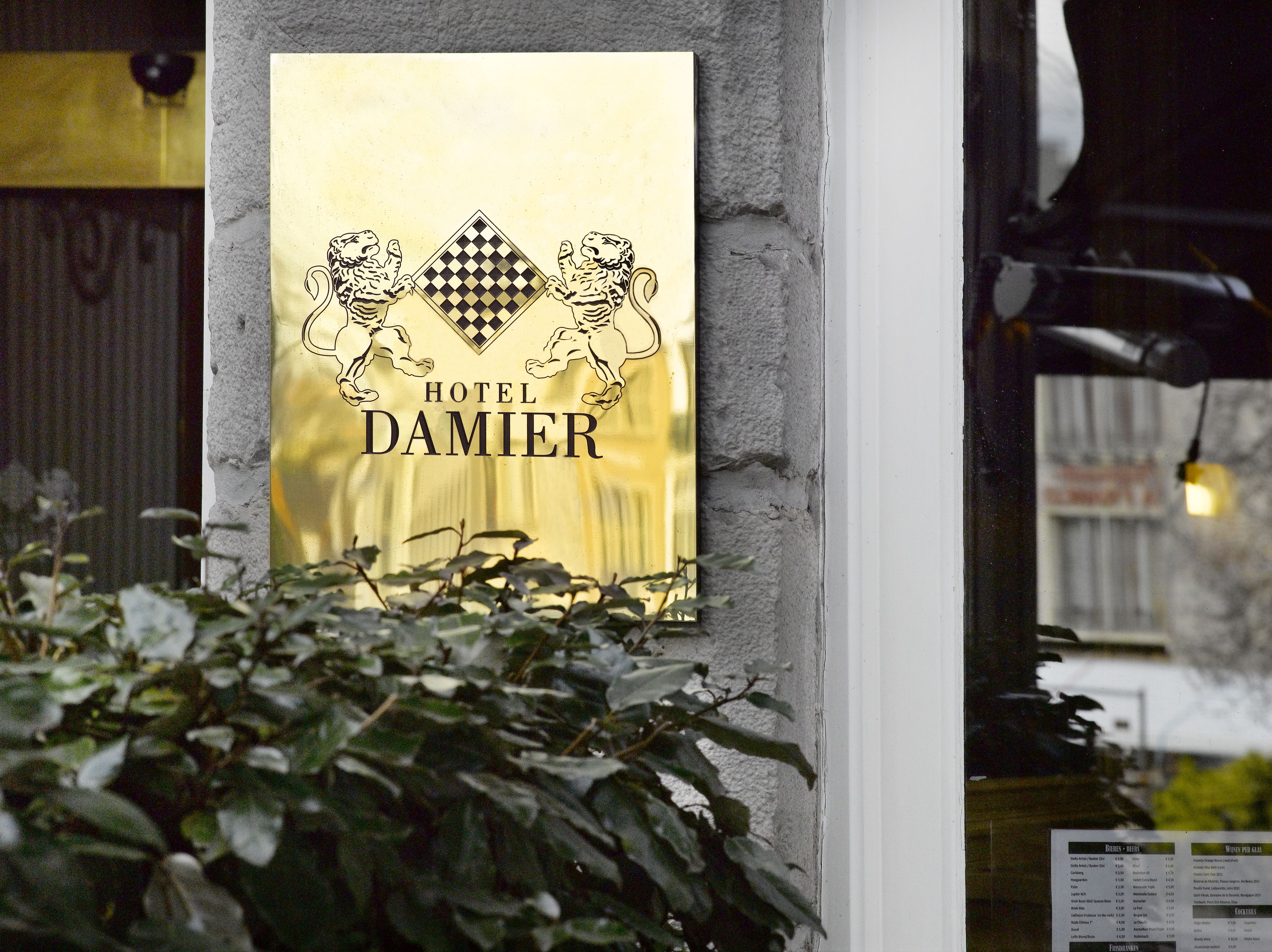 Een hotelschild met een geruit patroon en twee tijgers, waarop de naam 'Hotel Damier' staat.