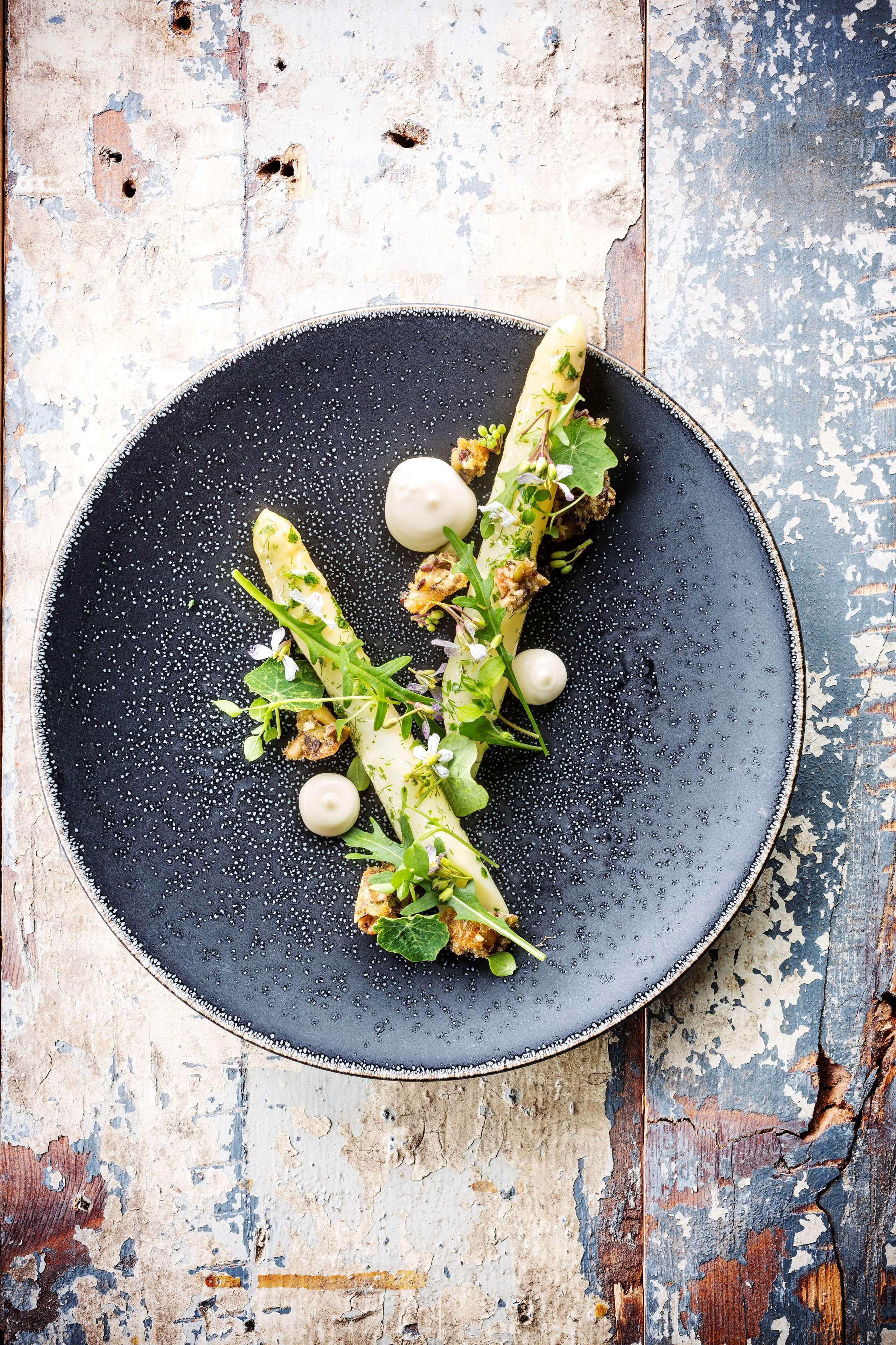 Une assiette contenant des asperges et des légumes verts, posée sur une table en bois rustique.