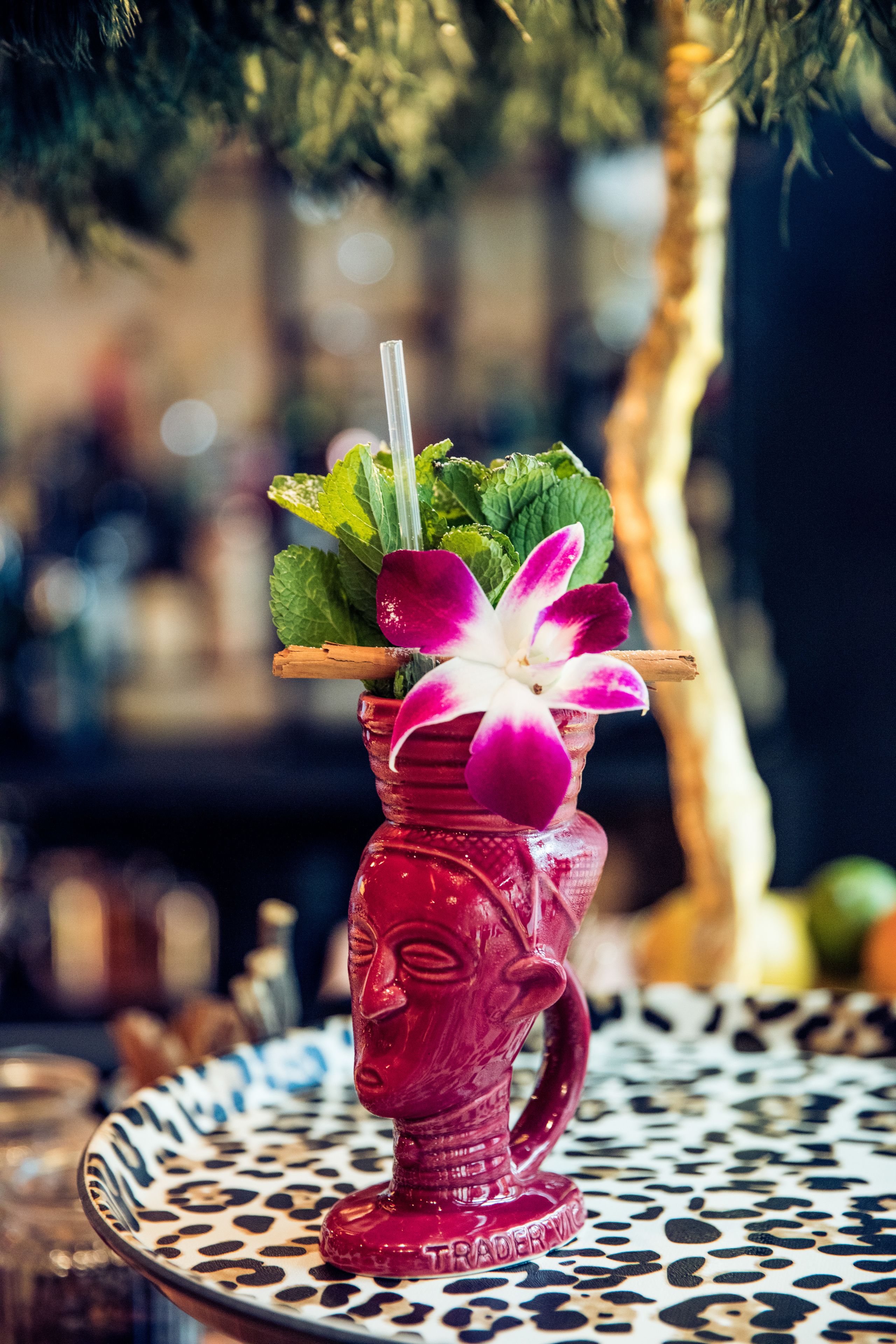 Um cocktail num copo decorativo sobre uma mesa estampada.