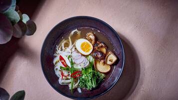 Kulho ramen-nuudelikeittoa, jossa on erilaisia lisukkeita, kuten nuudeleita, kananmuna, sieniä ja kasviksia.