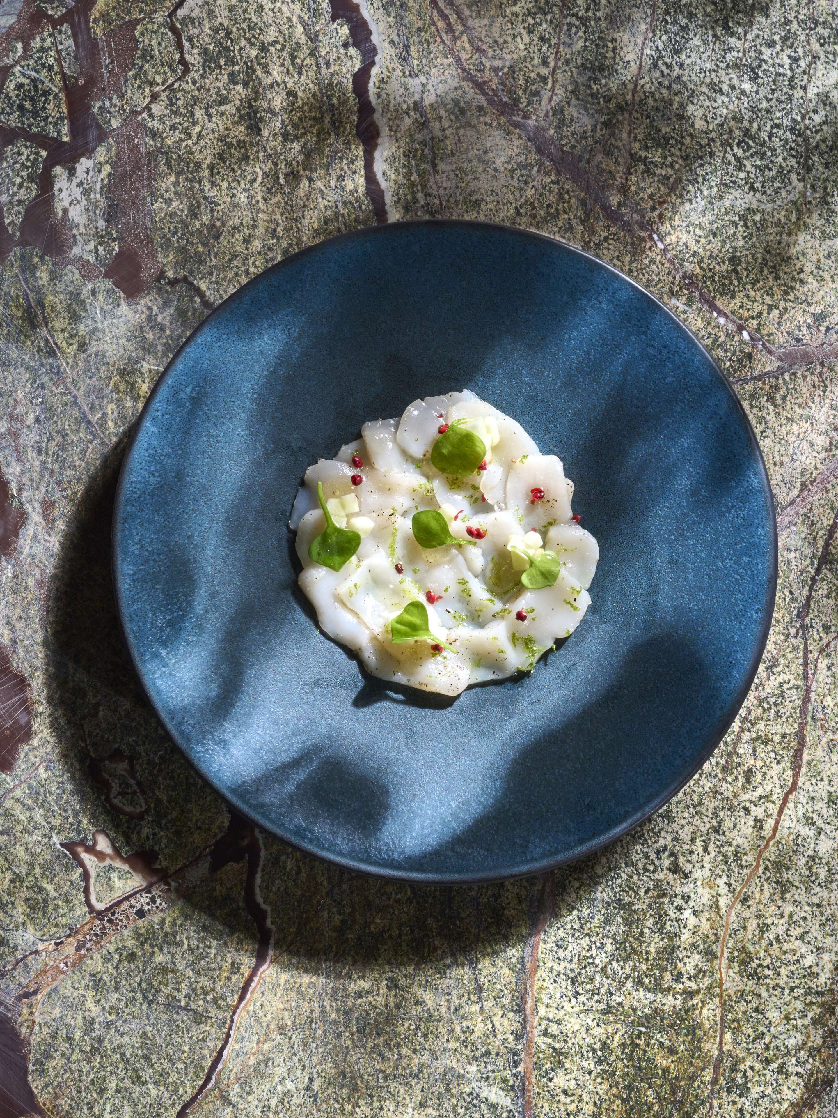 Un plat blau amb un bol blanc sobre una superfície rugosa.