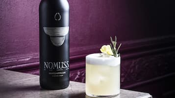 Una botella de Nomuss Margarita Mix y un cóctel sobre una barra de mármol.
