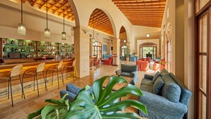A spacious lobby with a bar area, comfortable seating, and a wooden ceiling. - Pula Suites Boutique Resort (Son Servera)