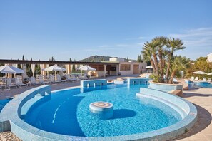 Una piscina techada, una piscina al aire libre, sombrillas