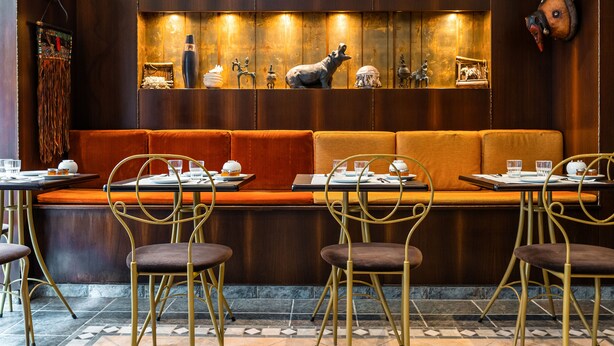 A restaurant with a wooden wall, a bench, and metal chairs.