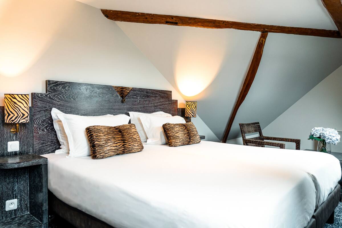 A bedroom with a large bed, dark wood headboard, and two wall-mounted lamps with zebra-patterned shades.