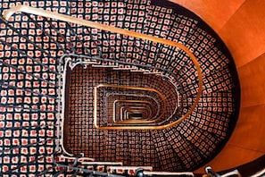 A spiral staircase with a patterned floor and metal railings. - Pavillon Opera Grands Boulevards (Paris)
