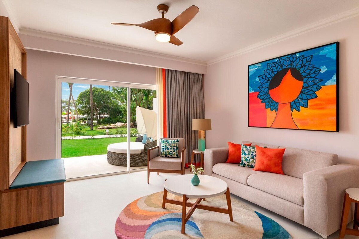 A modern living room with a sofa, armchair, coffee table, and a painting.