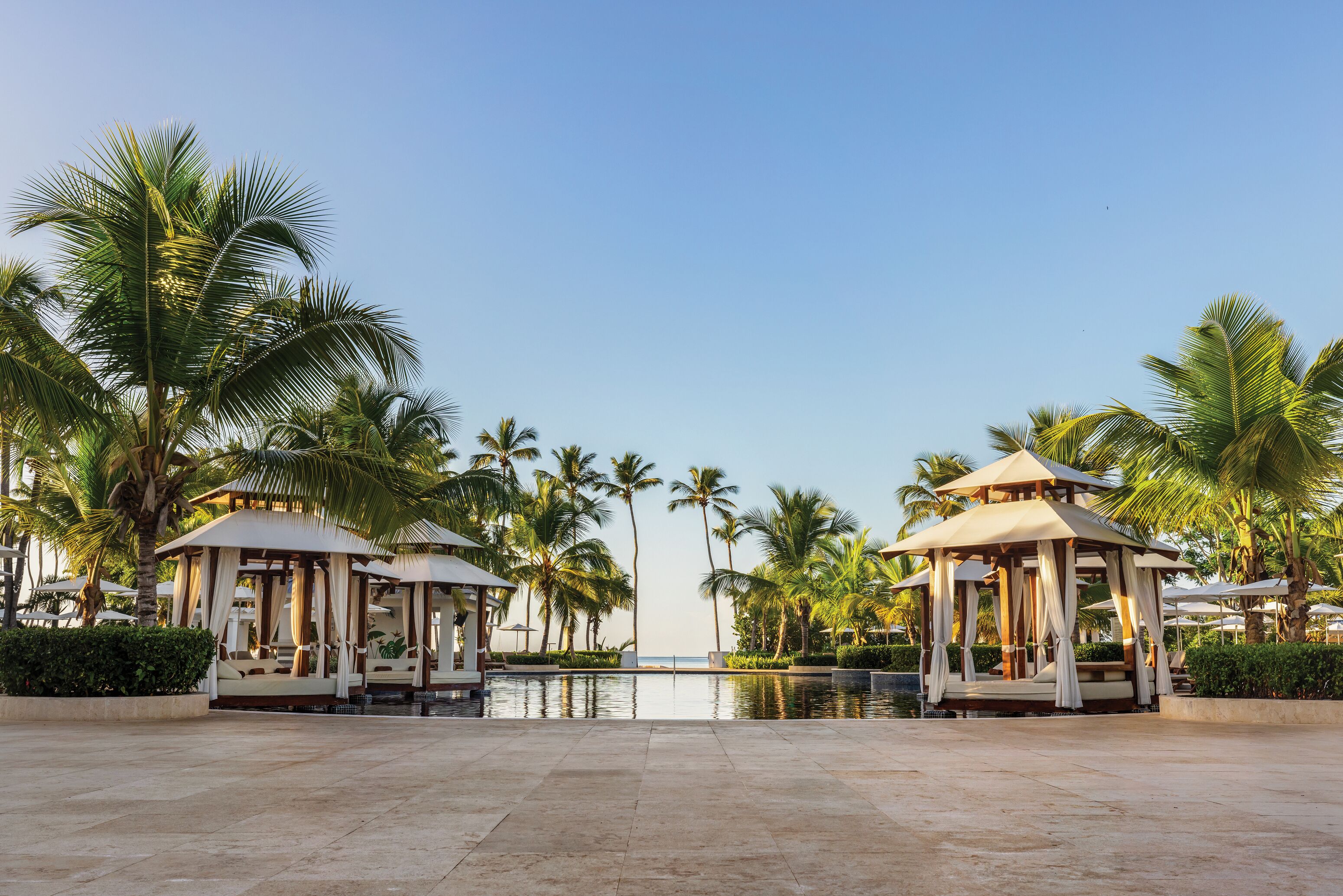 Un resort con dos pabellones, palmeras y una piscina.