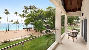 A balcony with a view of a beach, palm trees, and a lounge area with chairs and umbrellas. - Dreams La Romana Resort & Spa - All Inclusive (San Rafael del Yuma)