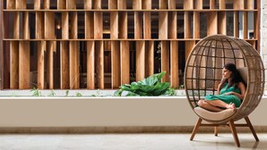 A room with a large window, a wicker chair, and a wooden slat wall. - Dreams La Romana Resort & Spa - All Inclusive (San Rafael del Yuma)