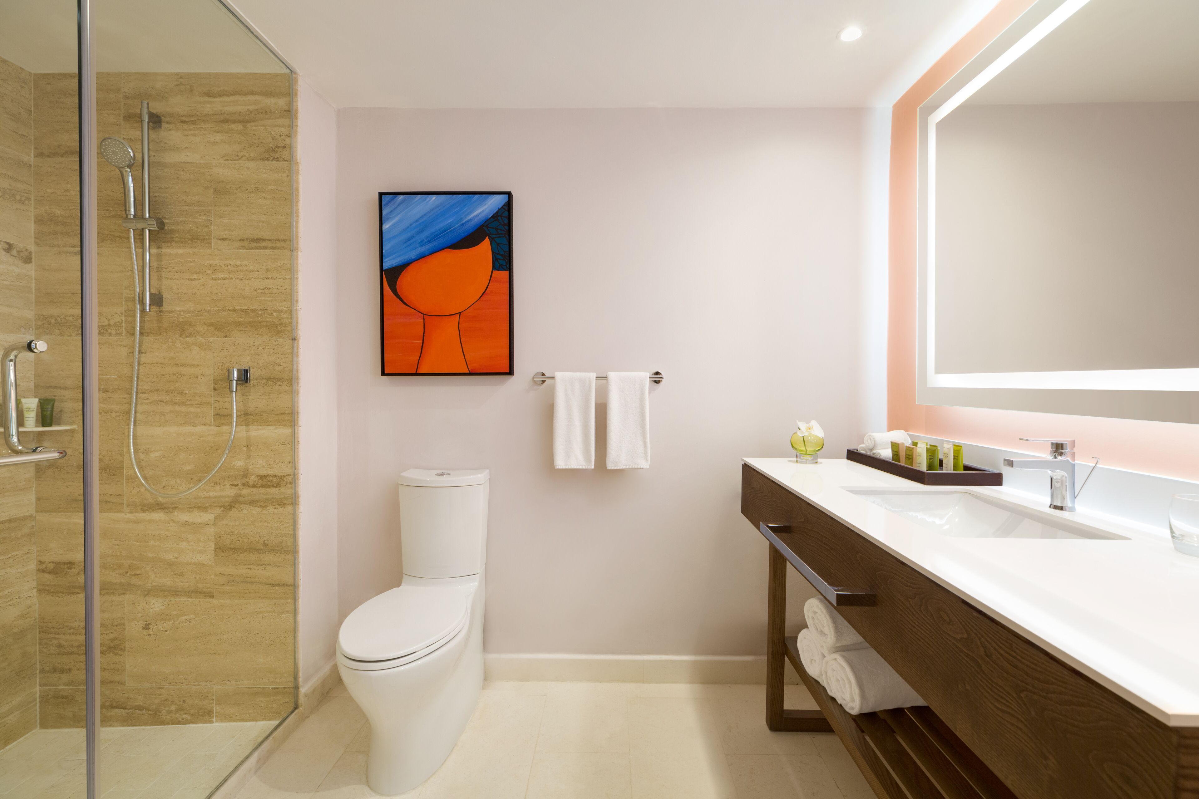 A modern bathroom with a glass shower enclosure, a toilet, a sink with a mirror, and a towel rack.