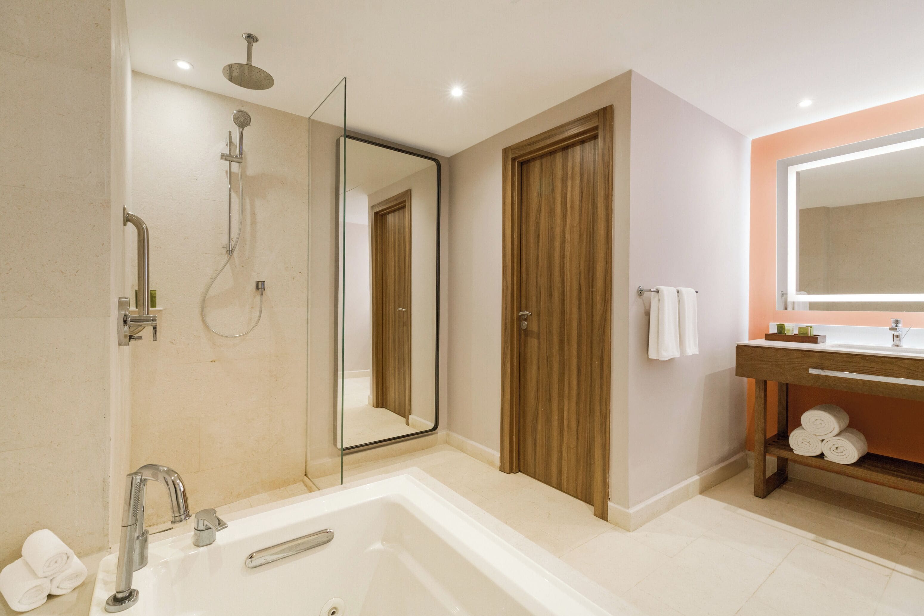 A modern bathroom with a bathtub, a shower, a vanity with a mirror, and a towel rack.