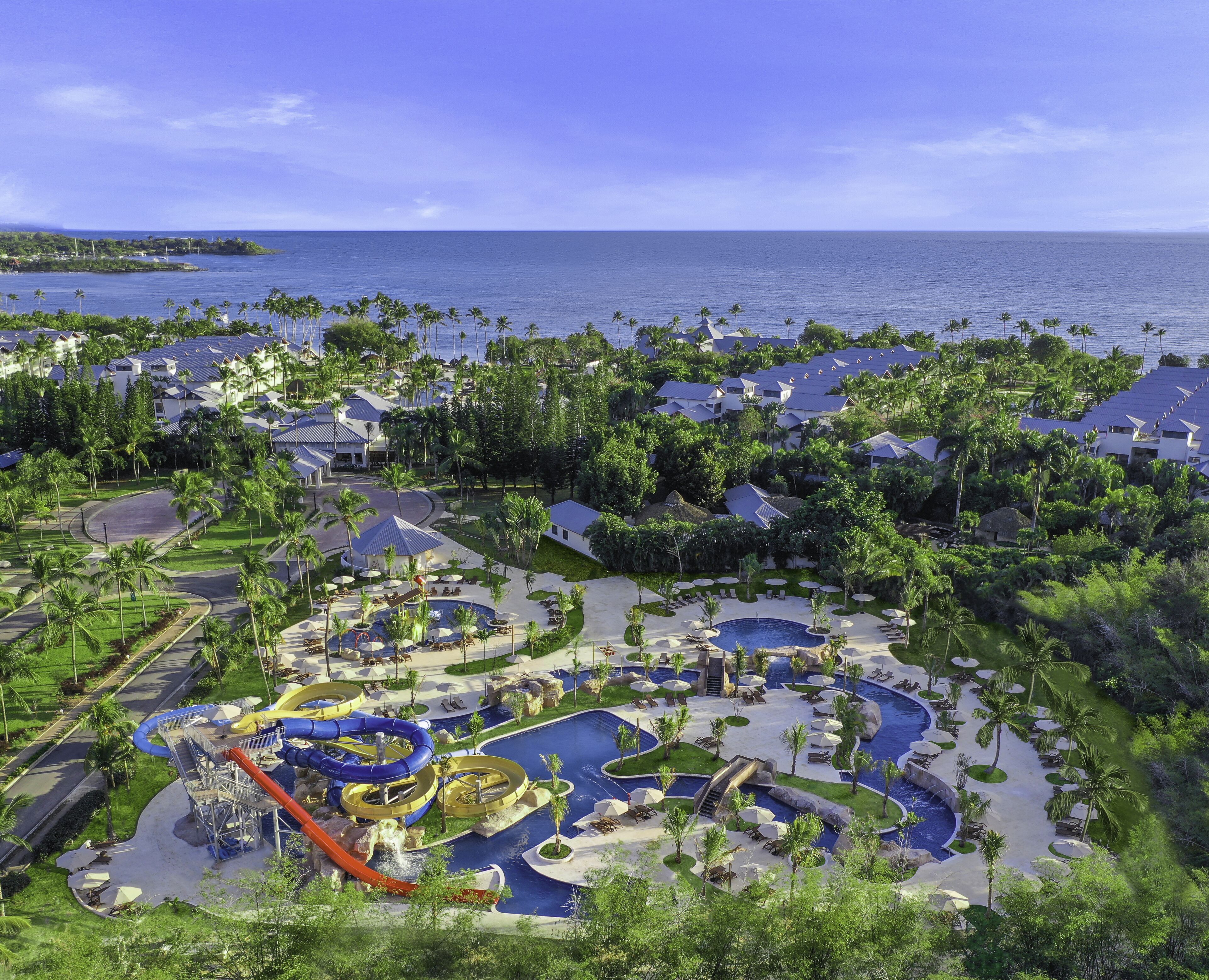 Ein Resort mit großem Poolbereich, Wasserrutschen und Blick auf den Ozean.