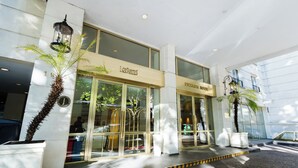 Ein Hotel Eingang mit Glastüren, einem Schild mit der Aufschrift "LOISUITS" und einem Schild mit der Aufschrift "BICOLLETIER HOTEL".